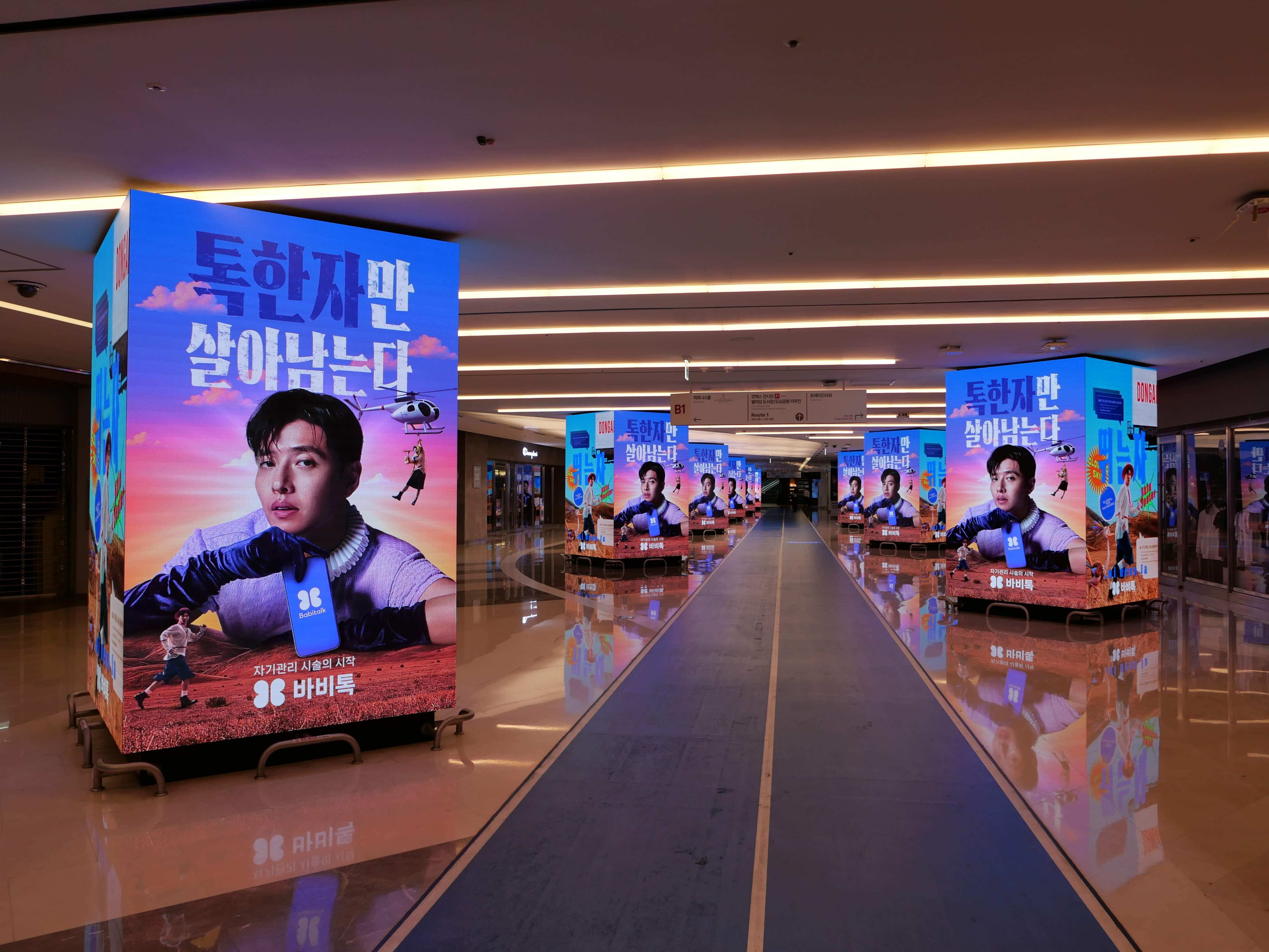 Rows of freestanding BABITALK digital displays reflected on the floor along the COEX 9TO9 corridor, Seoul