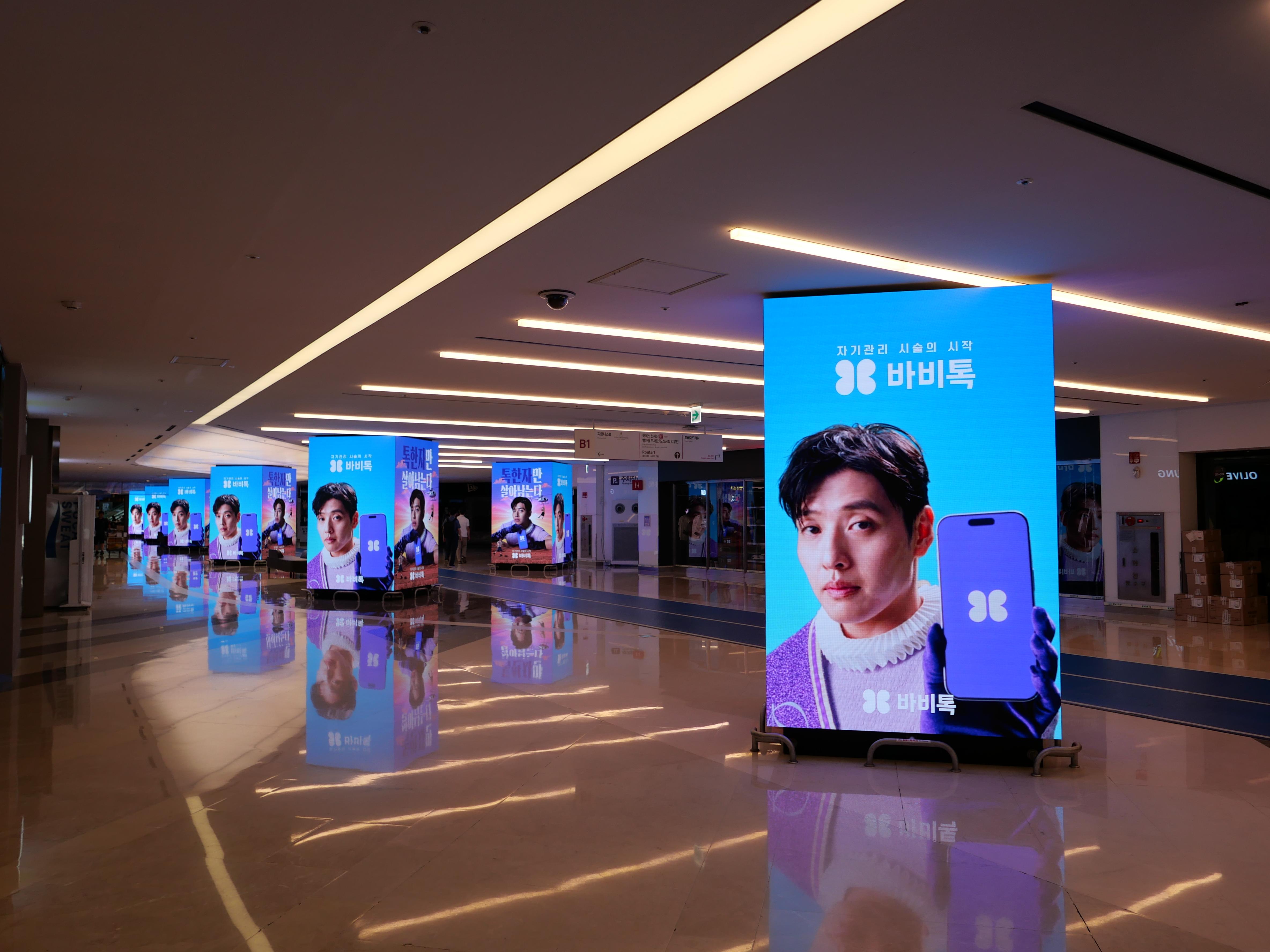 BABITALK creative on a tall COEX 9TO9 digital display with a line of displays receding behind, Seoul