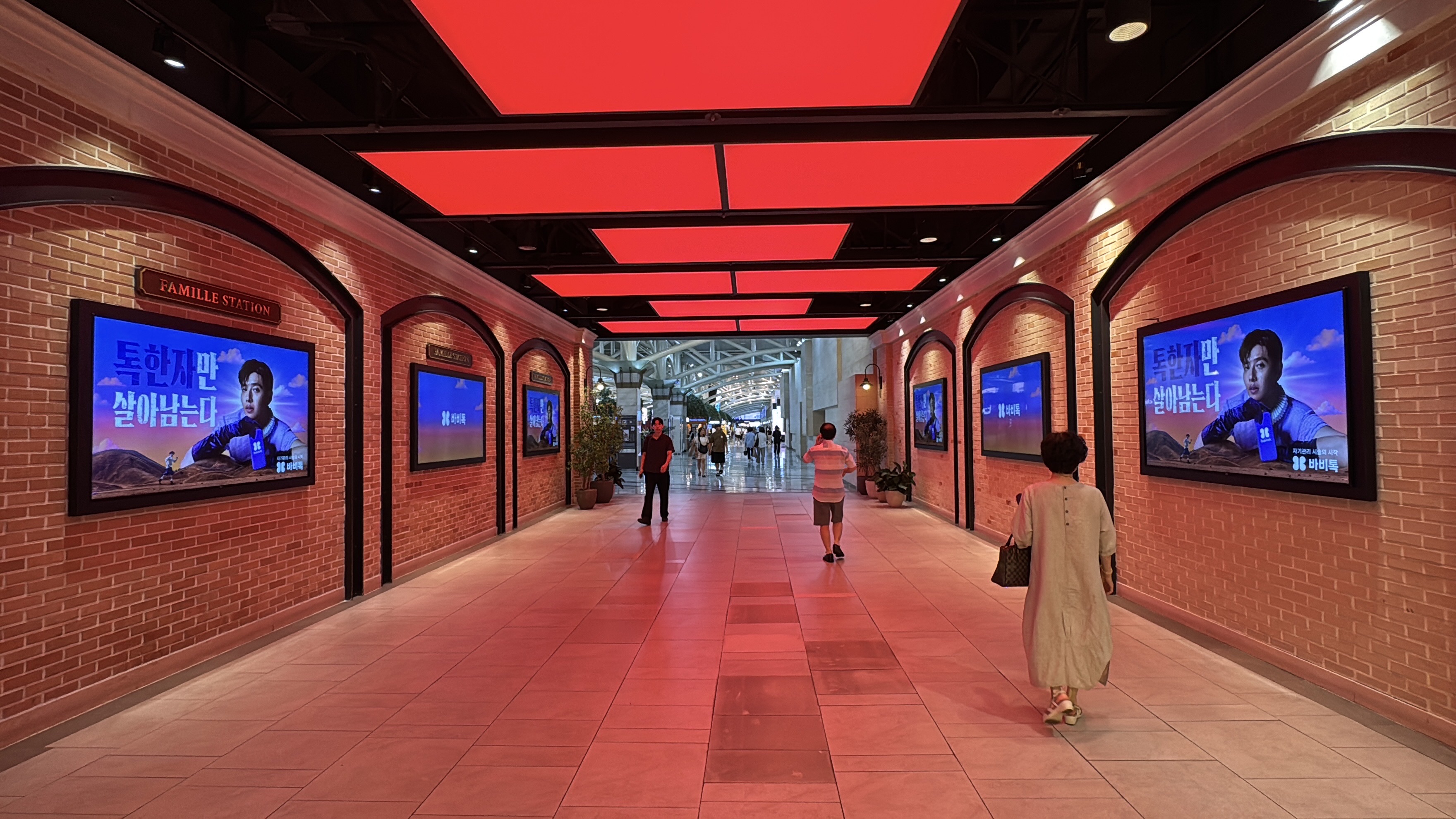 BABITALK digital screens set into arched brick walls on both sides of the Famille Station corridor, Seoul
