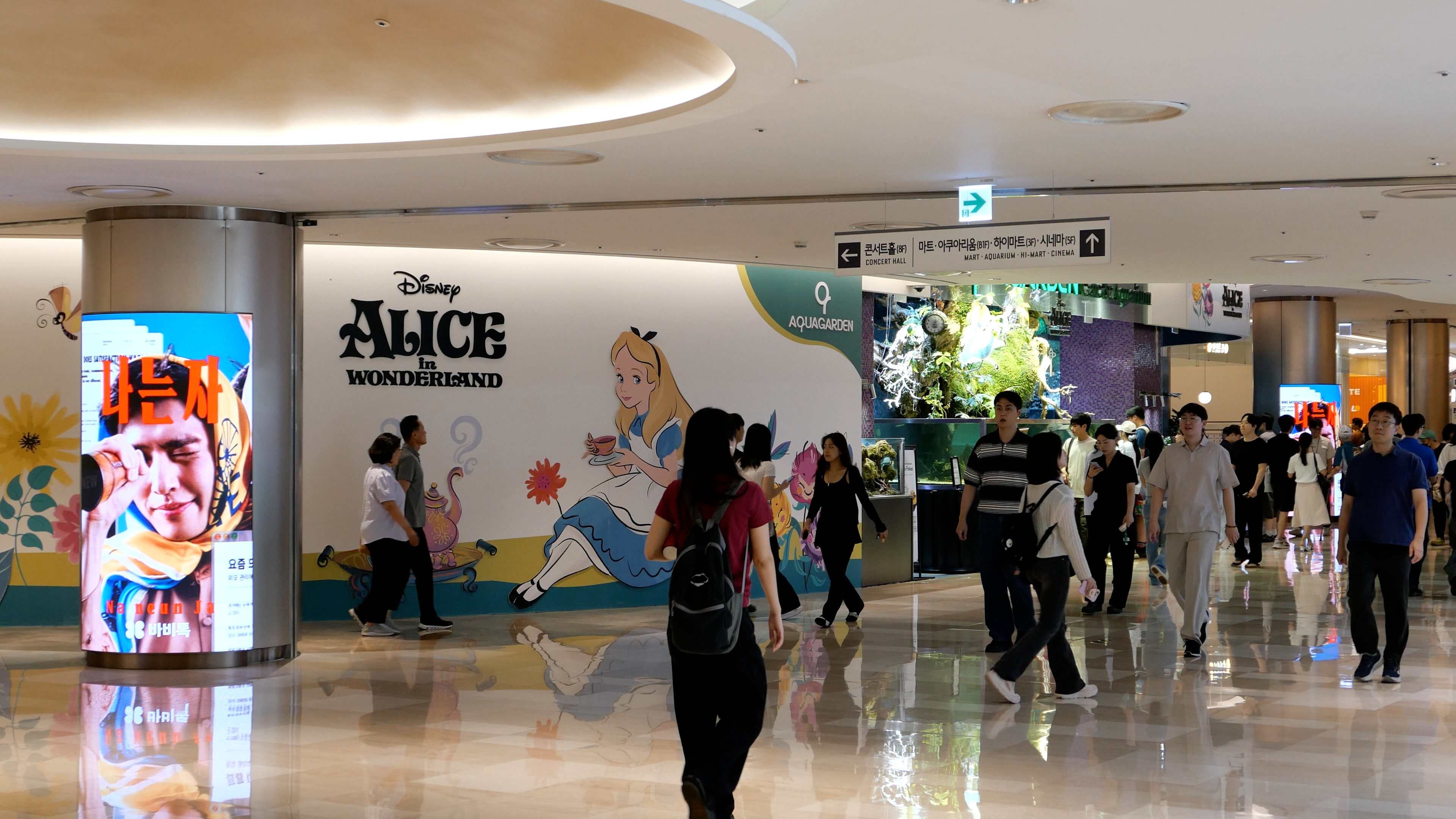 BABITALK creative on a curved digital column next to a themed wall mural, Lotte World Mall, Jamsil