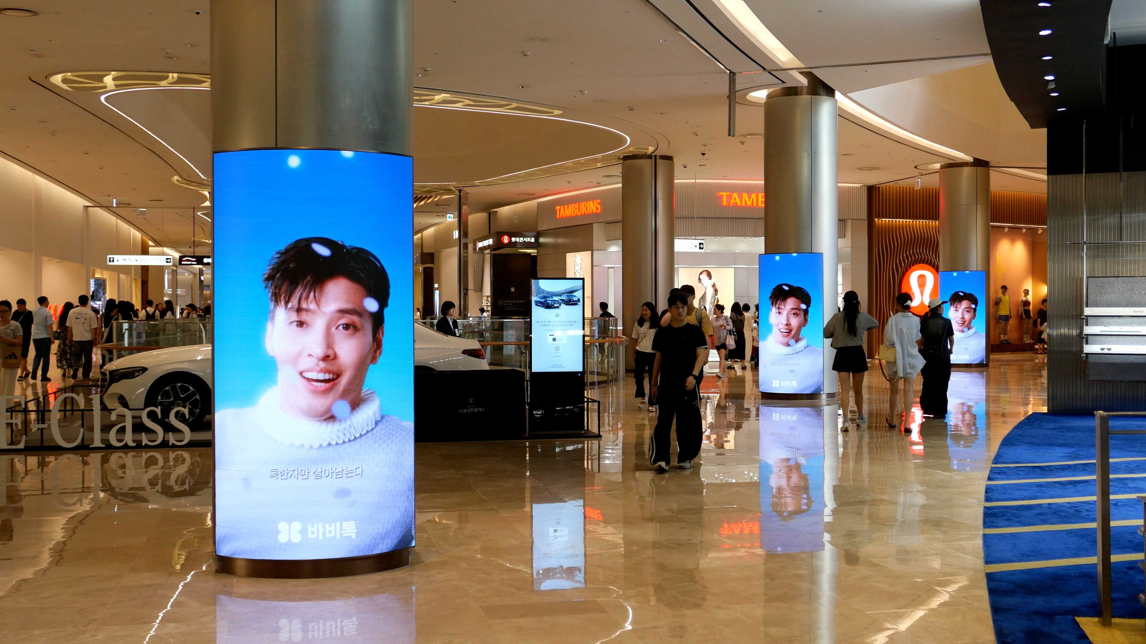 Sequence of curved BABITALK digital columns showing the same creative across the Lotte World Mall concourse, Jamsil