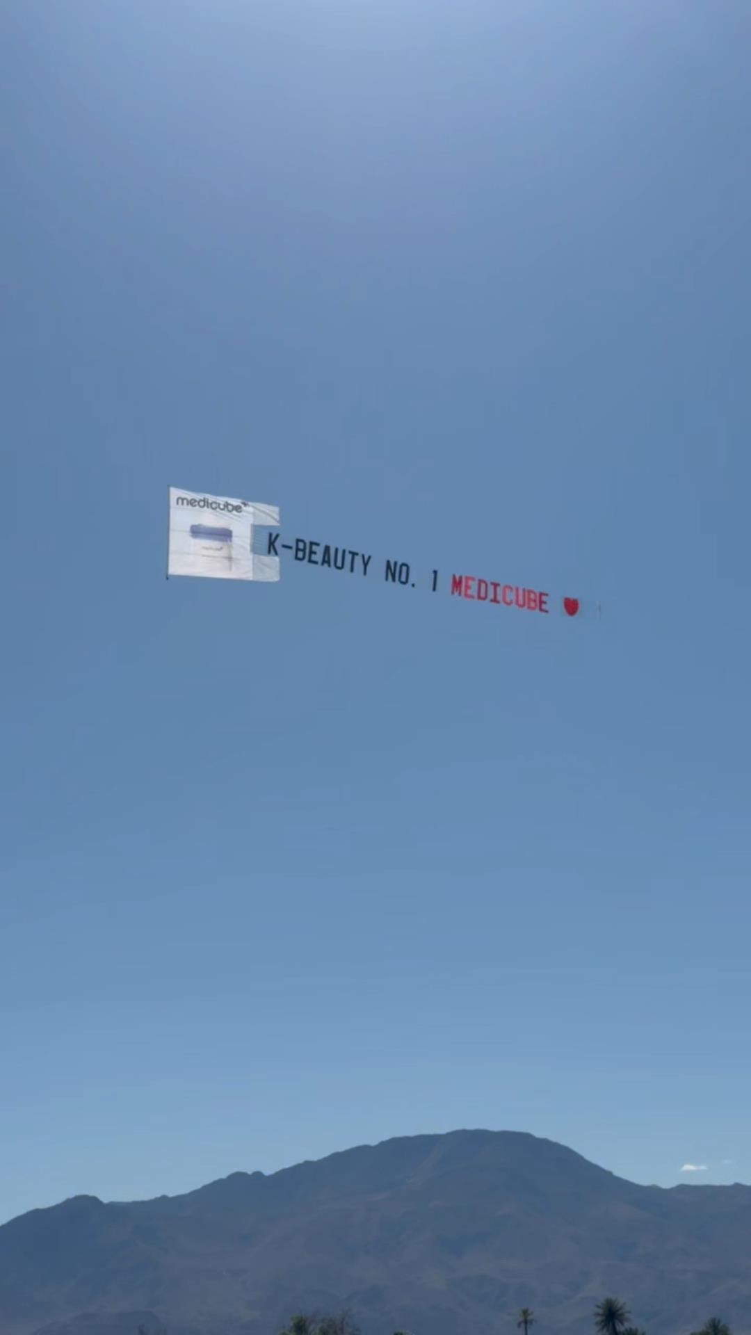 “K-BEAUTY NO. 1 MEDICUBE” aerial banner against a clear desert sky