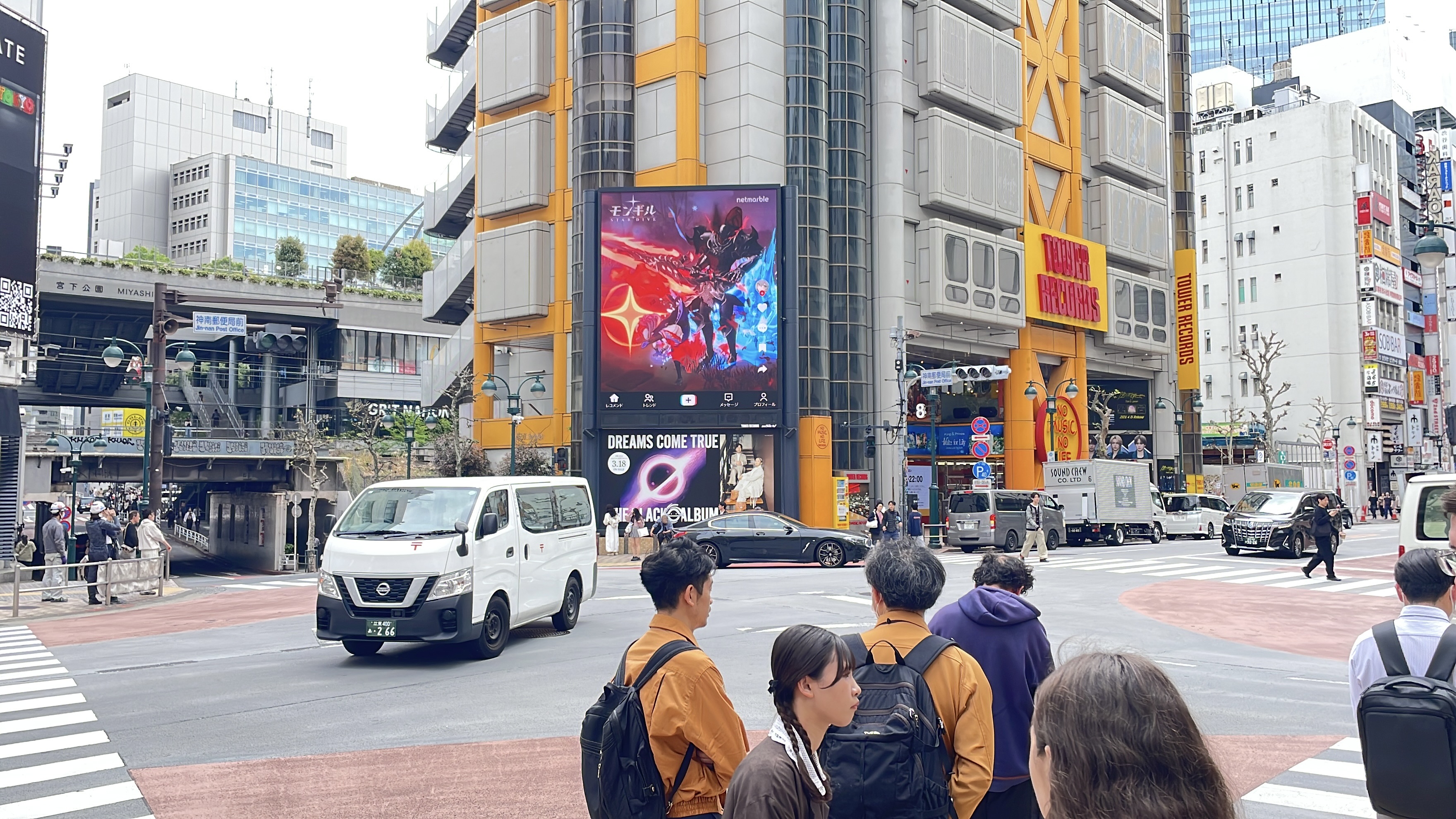 MONGIL: STAR DIVE battle creative on the Tower Records Shibuya screen with pedestrians at the crossing, Tokyo