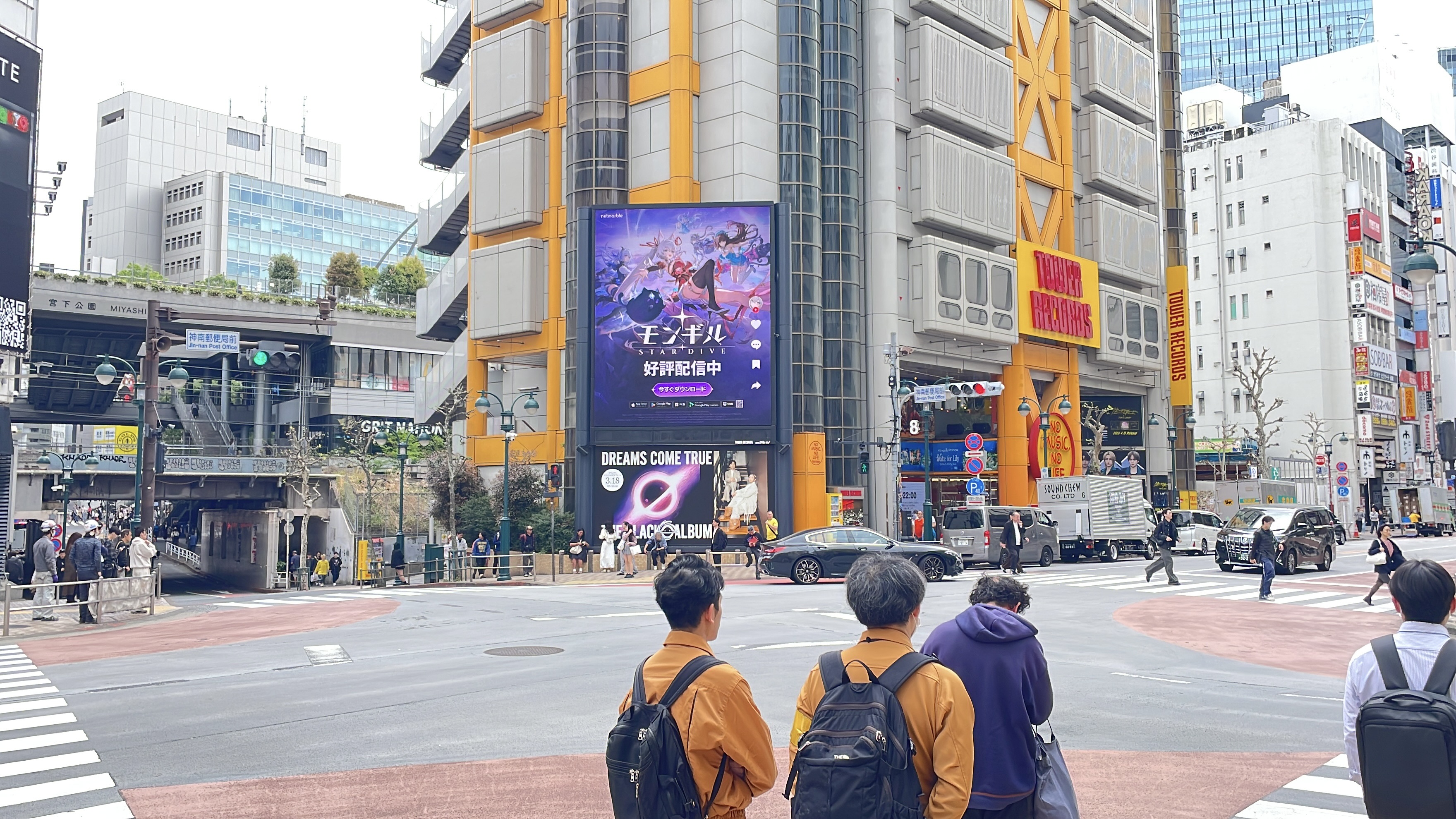 Wide street-level view of the Tower Records Shibuya building with the Japanese MONGIL: STAR DIVE creative on its screen, Tokyo