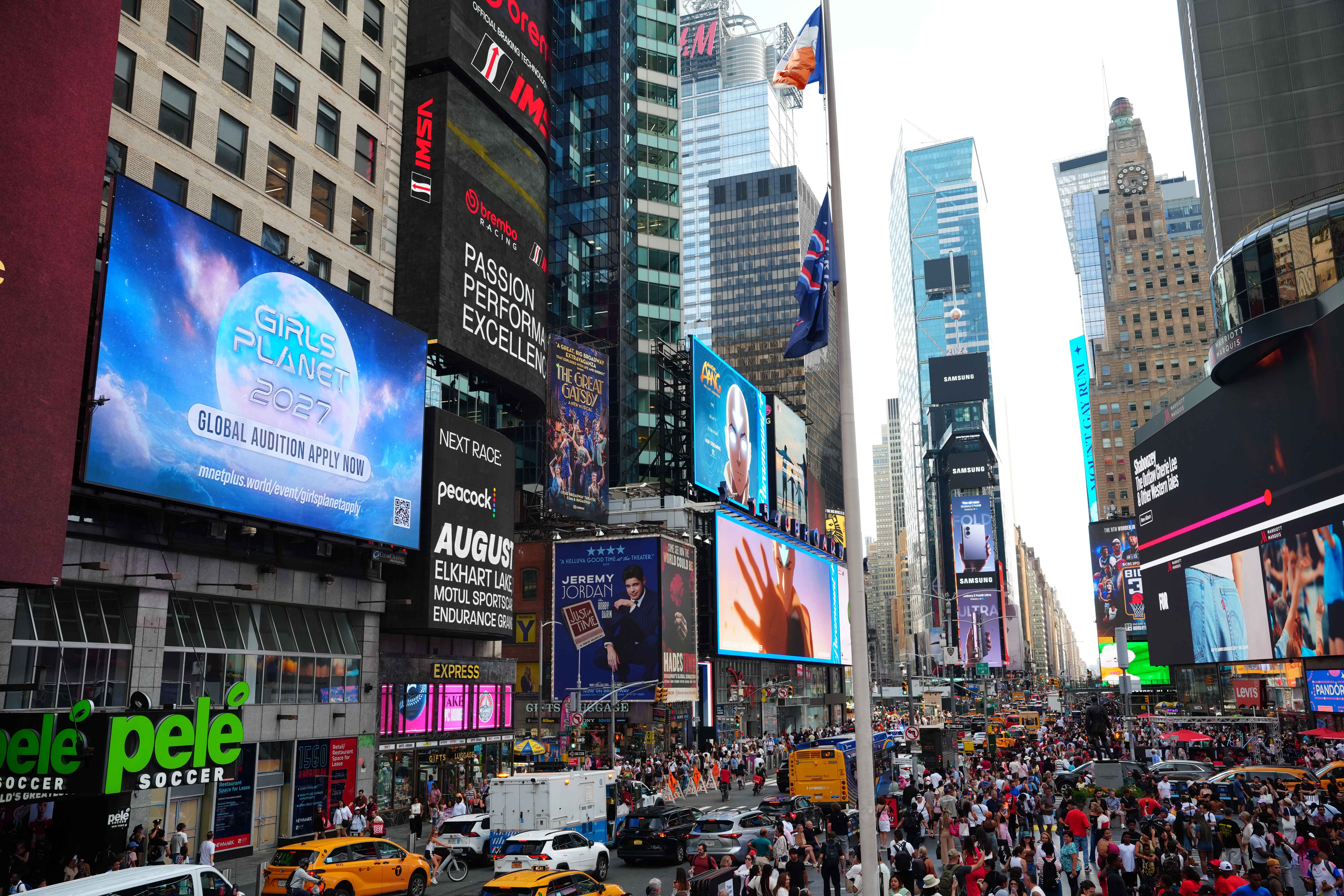 Mnet Girls Planet 2027 Global Audition campaign on a large Times Square screen, surrounded by digital billboards and crowds, New York