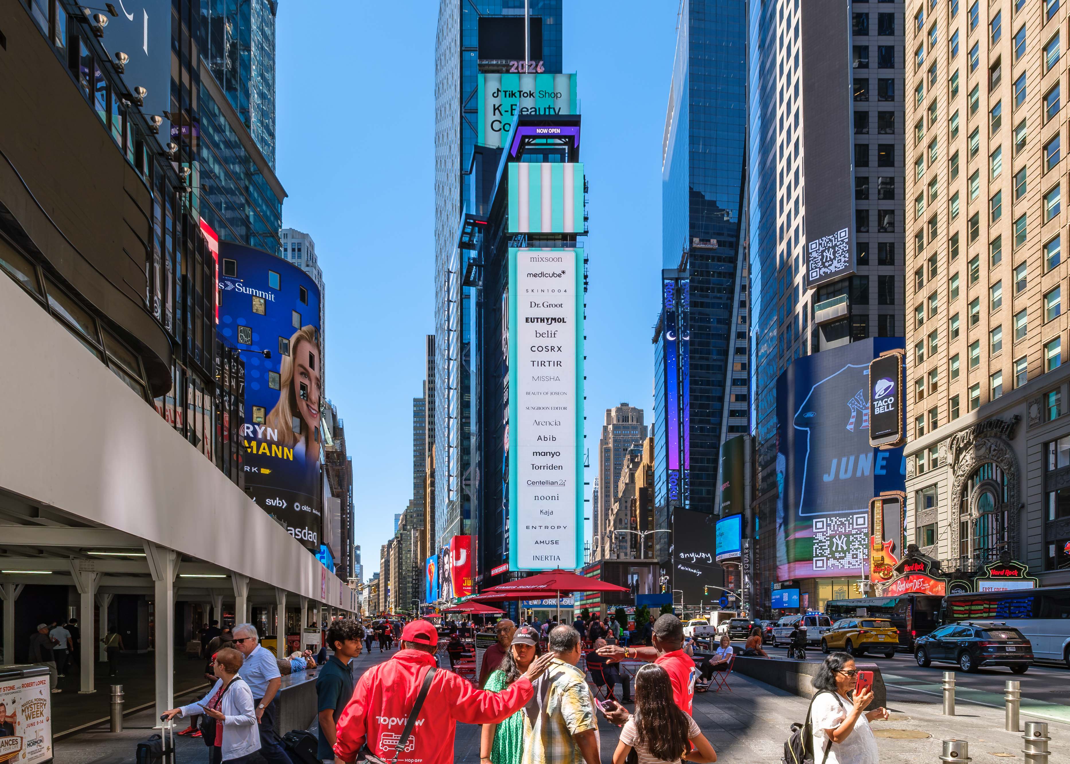 Vertical Times Square screen listing the K-Beauty Collective brands including mixsoon, medicube, SKIN1004, Dr. Groot, COSRX and TIRTIR