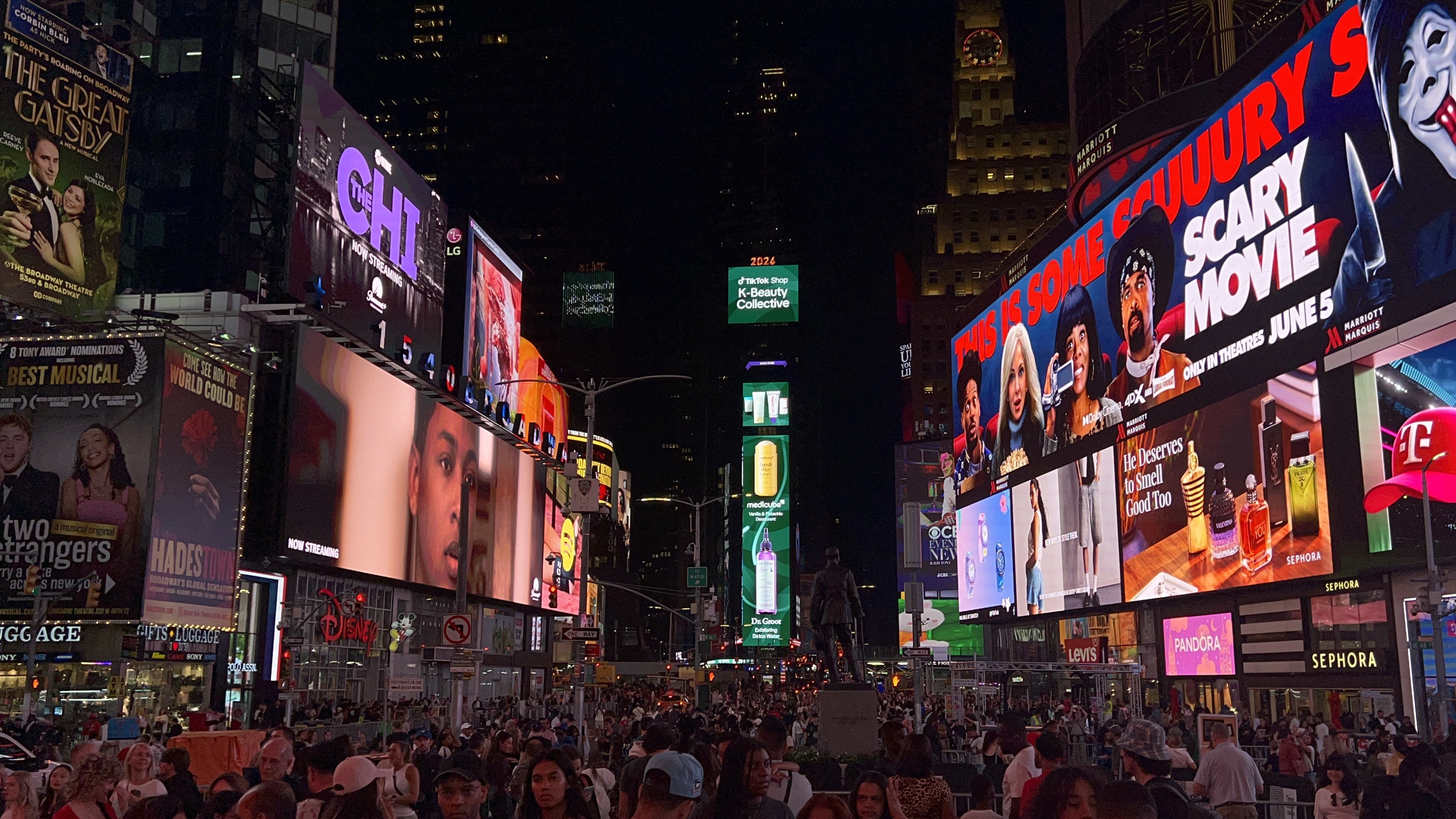 Times Square at night with crowds below and the TikTok Shop K-Beauty Collective creative glowing on the central vertical screens